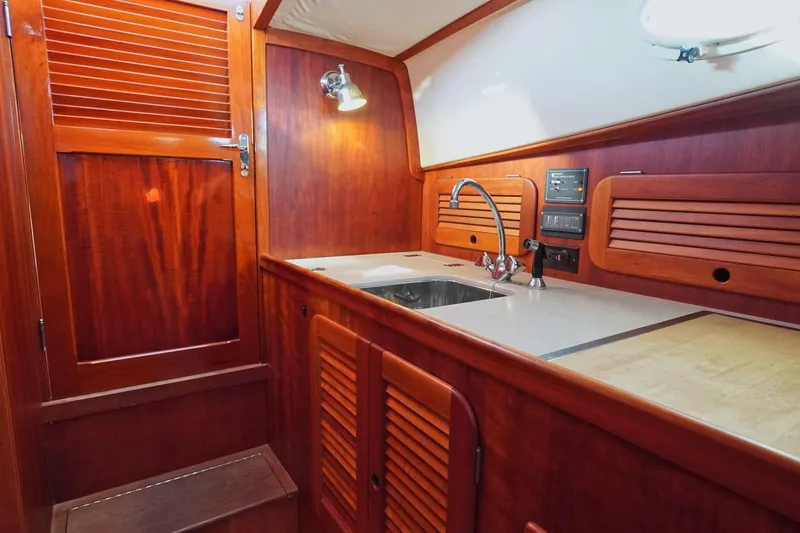 Slide: The Image of 2004 Hinckley Picnic Boat 36 EP interior with wooden cabinetry and compact kitchen area. - 19
