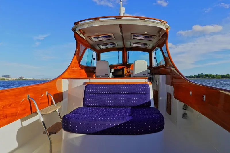 Slide: The Image of 2004 Hinckley Picnic Boat 36 EP interior with wooden finish and blue seating on water. - 7