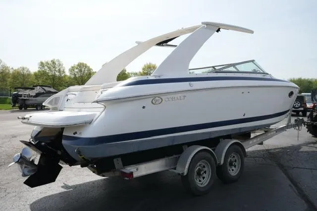 Slide: The Image of 2002 Cobalt 263 boat on trailer, white with blue accents, parked outdoors. - 5