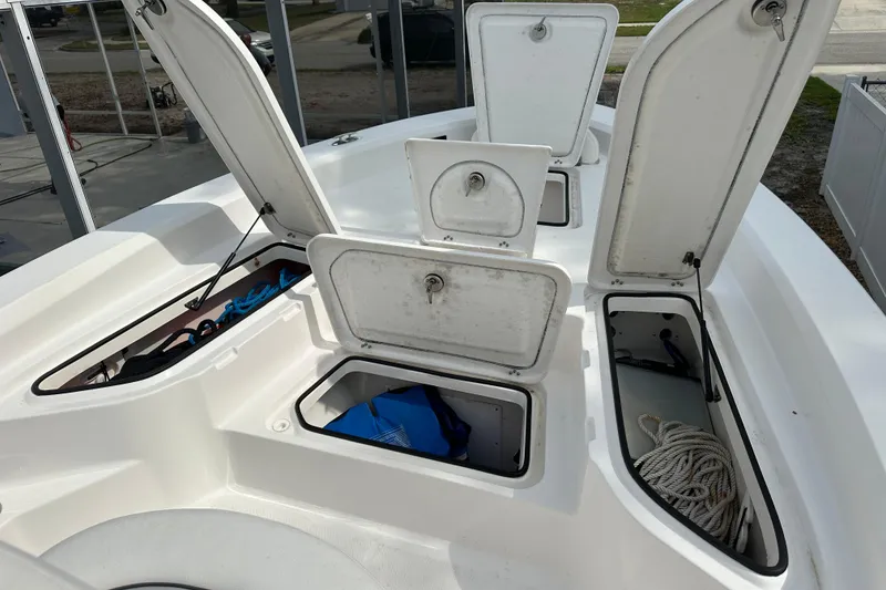 Slide: The Image of 2024 Aquasport 230 Pro Bay boat storage compartments open, showcasing interior space. - 15