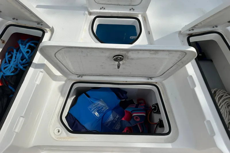 Slide: The Image of Open storage compartments on 2024 Aquasport 230 Pro Bay boat, containing ropes and life jackets. - 21