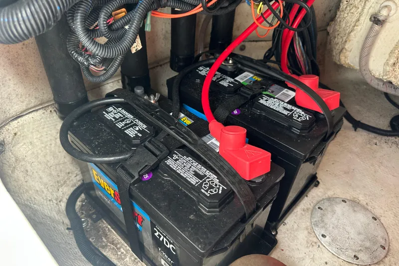 Slide: The Image of 2024 Aquasport 230 Pro Bay boat battery compartment with wiring and dual batteries. - 23