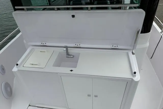 Slide: The Image of 2022 Axopar 28 Cabin boat kitchenette with sink and storage cabinets. - 13