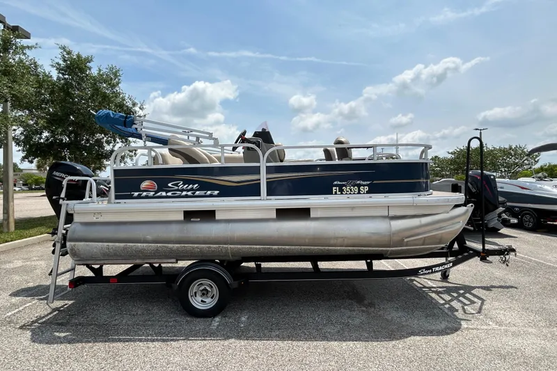 The Image of 2020 Sun Tracker Bass Buggy 16 DLX pontoon boat on trailer in parking lot. - 0