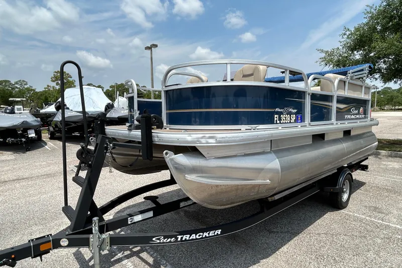 Slide: The Image of 2020 Sun Tracker Bass Buggy 16 DLX pontoon boat on trailer in parking lot. - 2