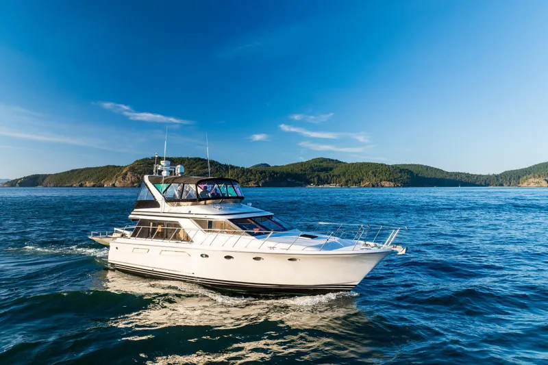 Slide: The Image of 1990 Ocean Alexander 48 Sedan yacht cruising on blue ocean near scenic coastline. - 13