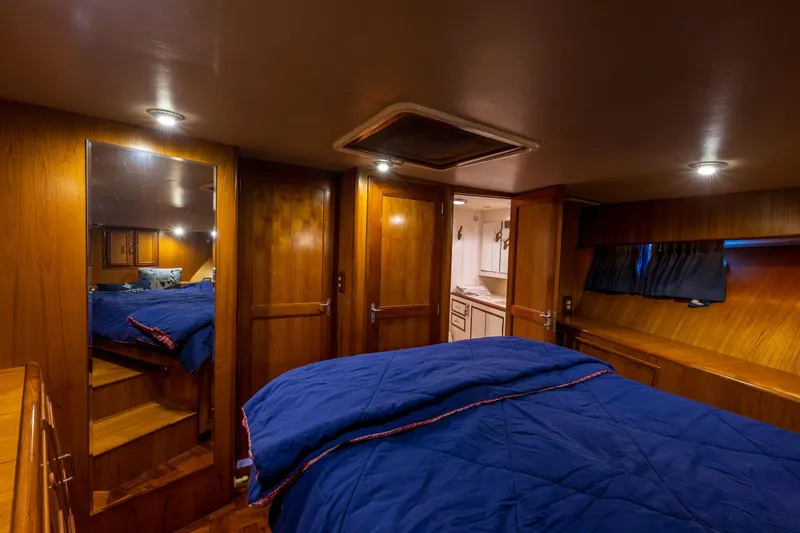 Slide: The Image of Luxurious 1990 Ocean Alexander 48 Sedan cabin with wood paneling and blue bedding. - 25