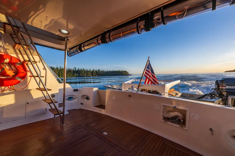 Slide: The Image of Ocean Alexander 48 Sedan yacht deck with American flag, ocean view, and sunset. - 37