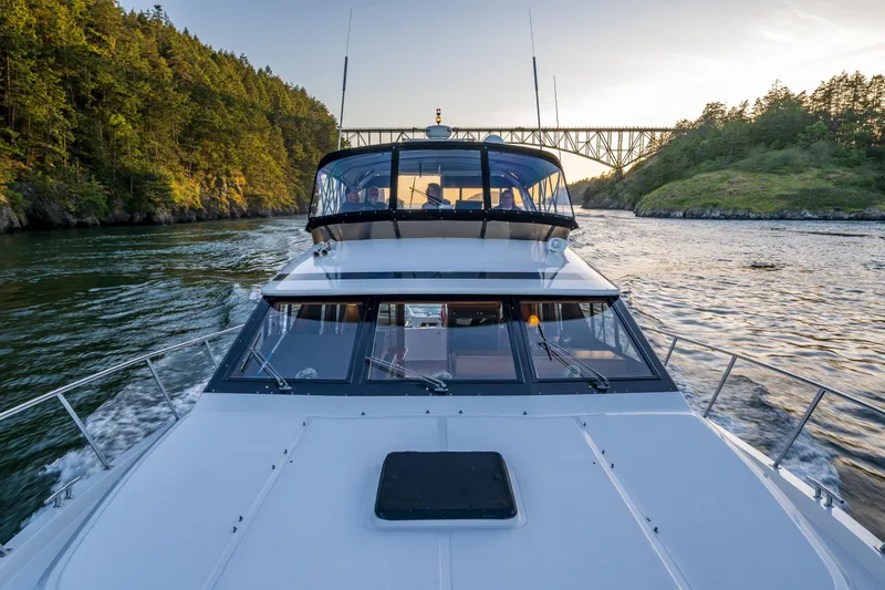 Slide: The Image of Ocean Alexander 48 Sedan cruising under a bridge, surrounded by lush greenery, 1990 model. - 42