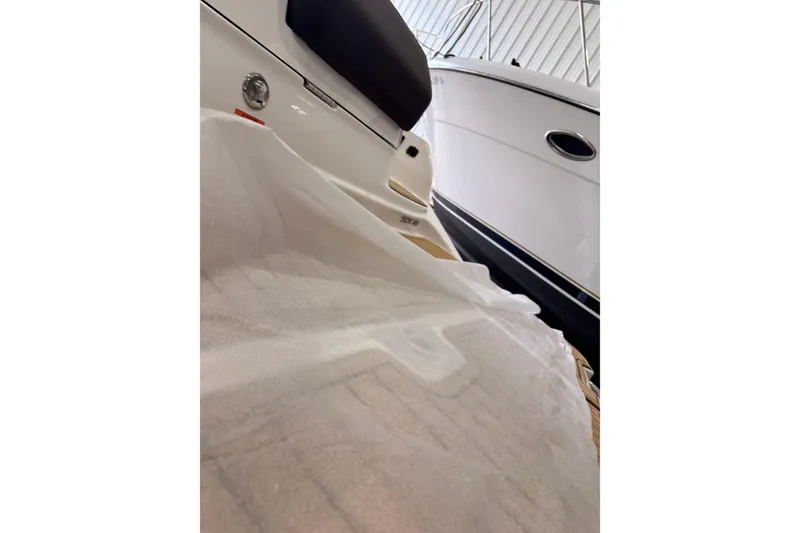 Slide: The Image of 2026 Searay 290 SDX boat in storage, partially covered, showcasing sleek design. - 15