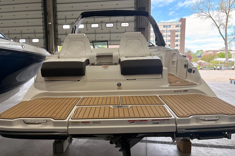 Slide: The Image of 2026 Searay 290 SDX boat with sleek seating and wooden deck in a showroom. - 5