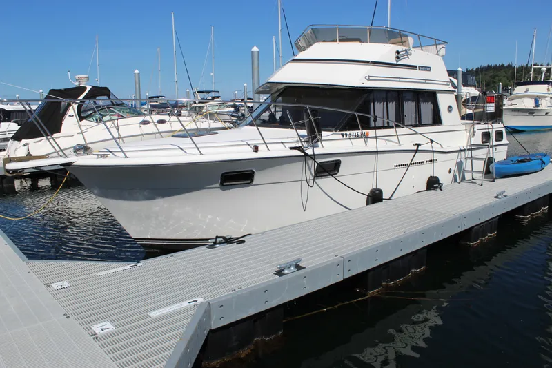 The Image of 1990 Carver 3207 Aft Cabin Motor Yacht docked at marina under clear blue sky. - 1