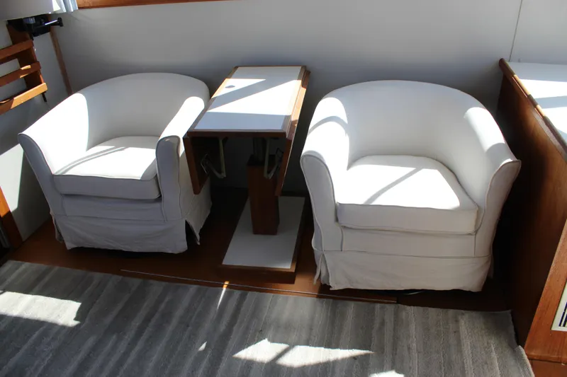 Slide: The Image of Interior of 1990 Carver 3207 Yacht with two white armchairs and a table. - 32
