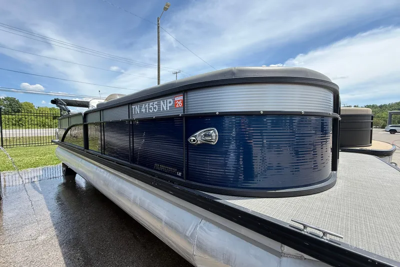 Slide: The Image of 2022 Manitou Aurora LE pontoon boat with blue exterior, docked on a sunny day. - 2