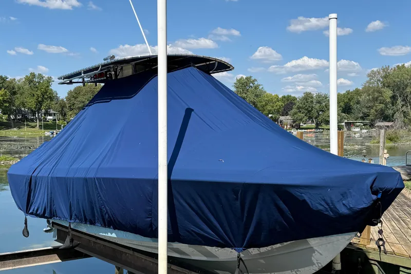 Slide: The Image of 2023 Bluewater Sportfishing 23t boat covered with a blue tarp at a dock. - 23