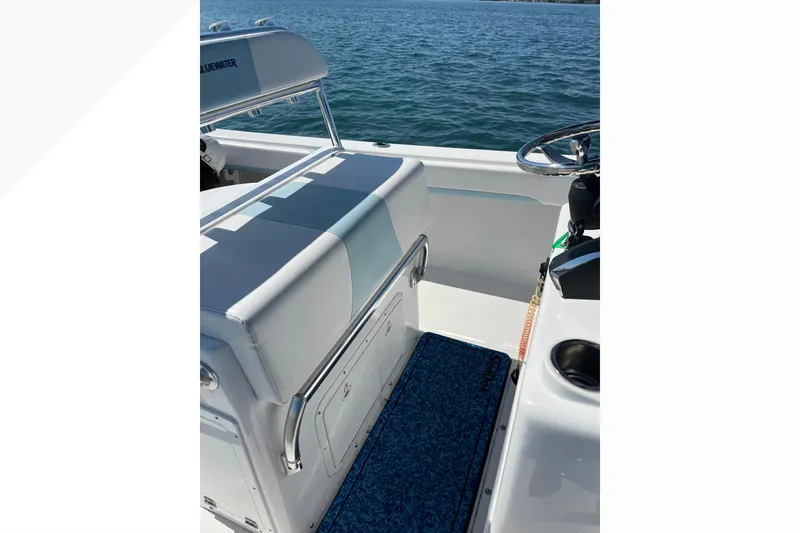 Slide: The Image of 2023 Bluewater Sportfishing 23t boat interior with seating and steering wheel on open water. - 9