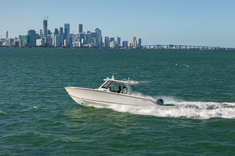 Slide: The Image of 2018 Pursuit S 328 Sport boat cruising near city skyline on open water. - 10