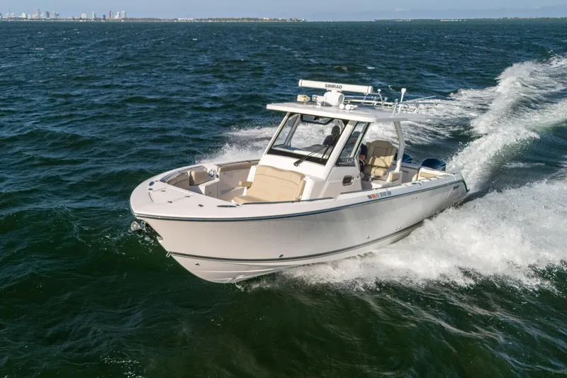 Slide: The Image of 2018 Pursuit S 328 Sport boat cruising on open water, city skyline in background. - 12