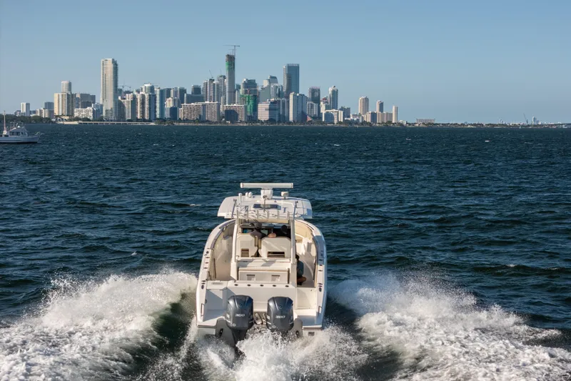 Slide: The Image of 2018 Pursuit S 328 Sport boat cruising with city skyline in background. - 13