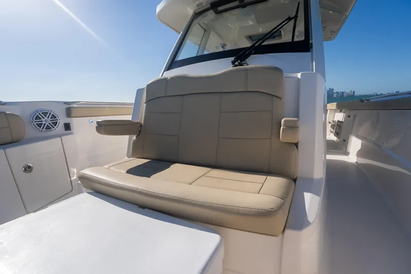 Slide: The Image of 2018 Pursuit S 328 Sport boat interior with beige seating and clear blue sky. - 14