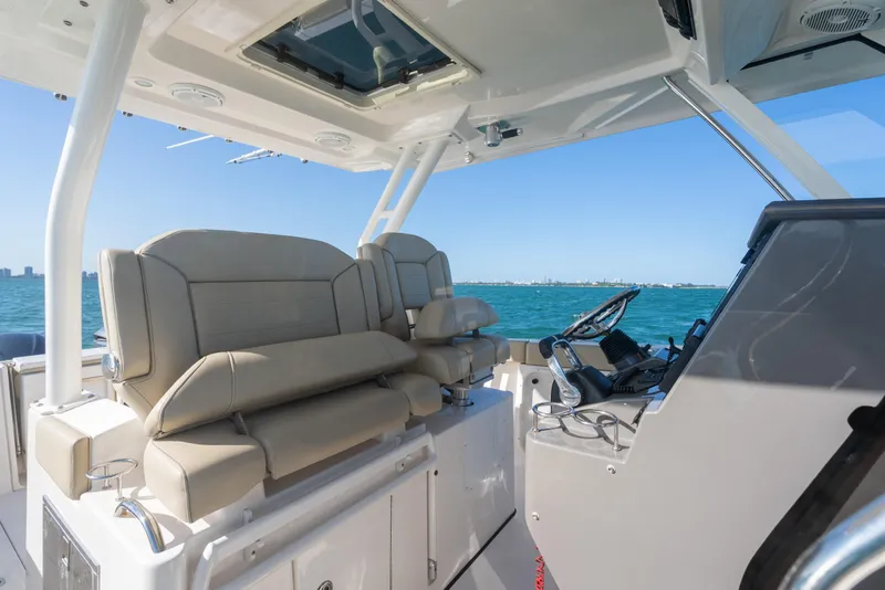 Slide: The Image of 2018 Pursuit S 328 Sport boat interior with helm and seating, overlooking ocean. - 31