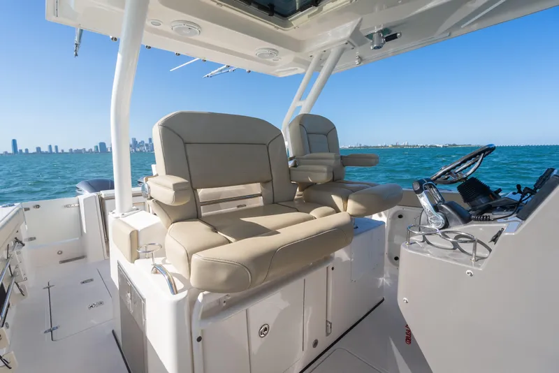 Slide: The Image of 2018 Pursuit S 328 Sport boat interior with beige seating and ocean view. - 33
