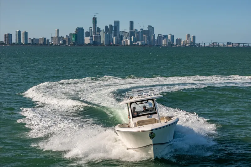 Slide: The Image of 2018 Pursuit S 328 Sport boat cruising near city skyline on open water. - 9
