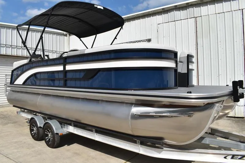 Slide: The Image of 2026 Lowe SS 230 WT Special pontoon boat with canopy on trailer, parked outdoors. - 9