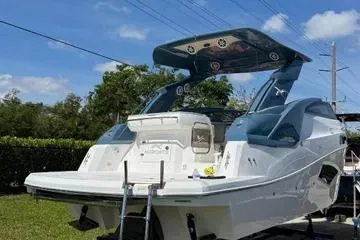 Slide: The Image of 2025 NX Boats NX290 Exclusive, sleek design, docked outdoors under blue sky. - 2