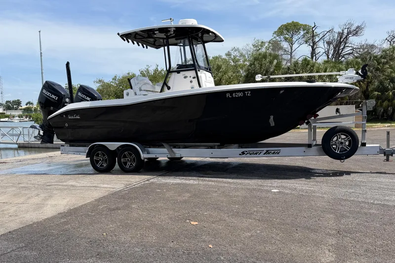 Slide: The Image of 2020 Sea Cat 260 boat on trailer with dual Suzuki engines, parked near a marina. - 2