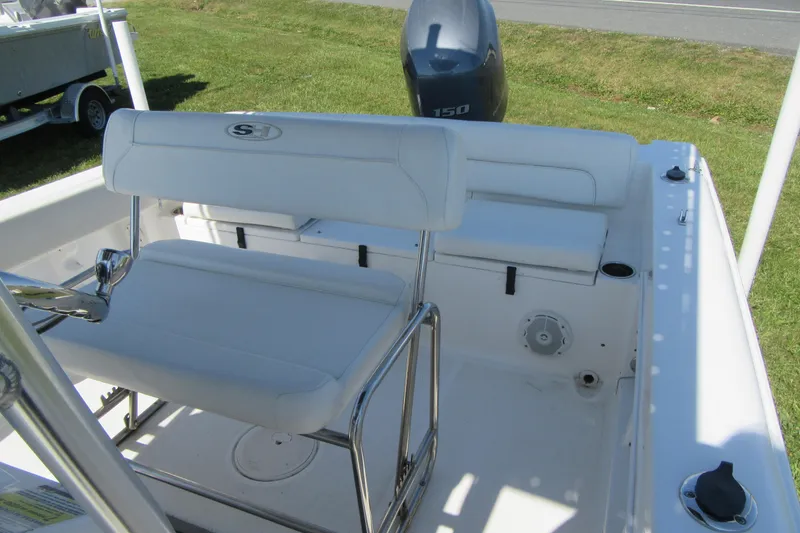 Slide: The Image of 2013 Sea Hunt Ultra 211 boat interior with seating and motor, parked on grass. - 16