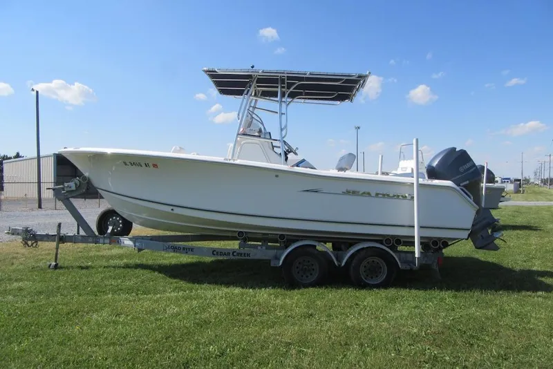 Slide: The Image of 2013 Sea Hunt Ultra 211 boat on trailer, parked on grass under blue sky. - 2