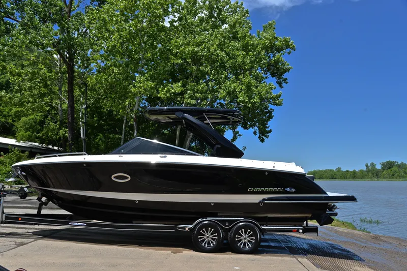 Slide: The Image of 2018 Chaparral 287 SSX boat on trailer by a lake, surrounded by trees. - 12