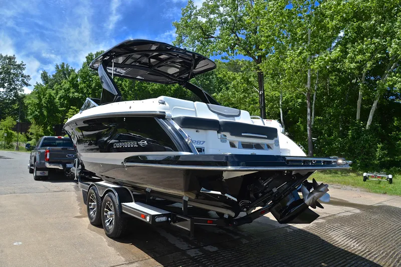 Slide: The Image of 2018 Chaparral 287 SSX boat on trailer, parked near lush green trees. - 13