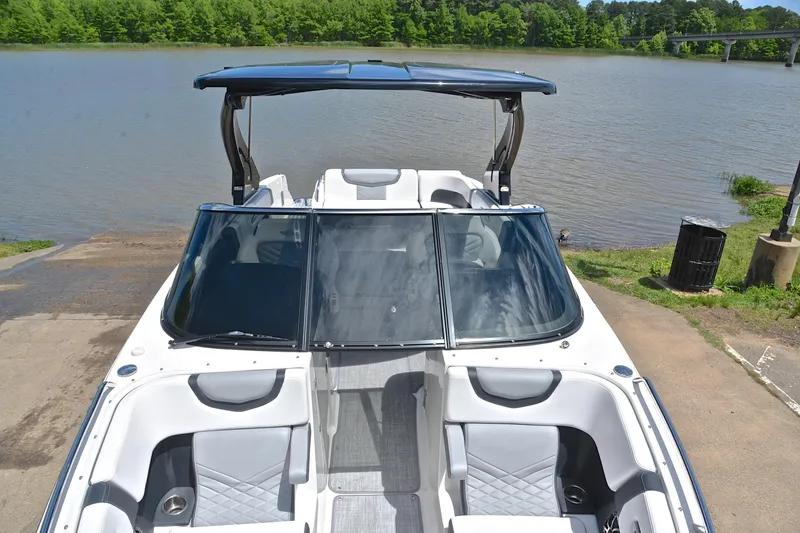 Slide: The Image of 2018 Chaparral 287 SSX boat at a lakeside dock, featuring sleek design and spacious seating. - 21