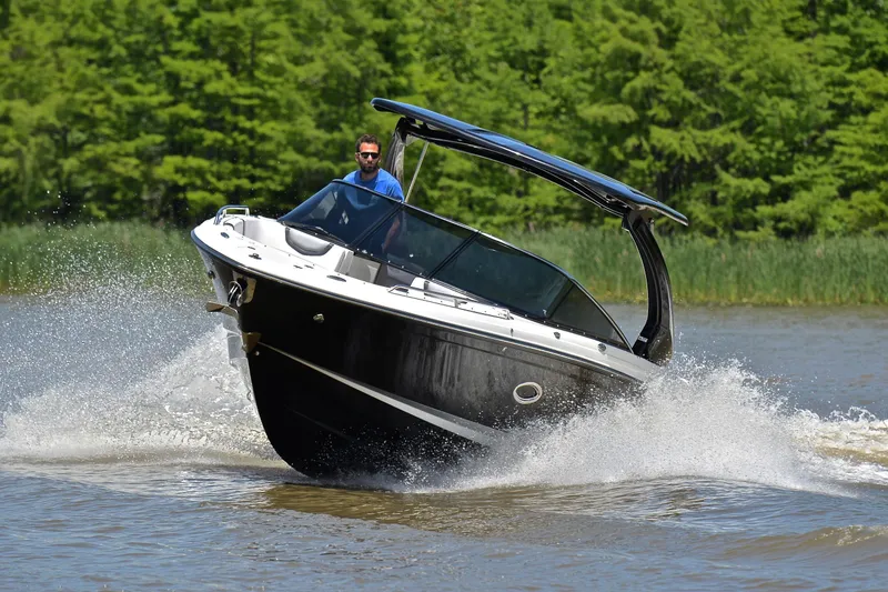 Slide: The Image of 2018 Chaparral 287 SSX boat cruising on a lake with lush green background. - 6