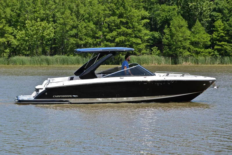 Slide: The Image of 2018 Chaparral 287 SSX boat cruising on a calm lake with lush green trees. - 8