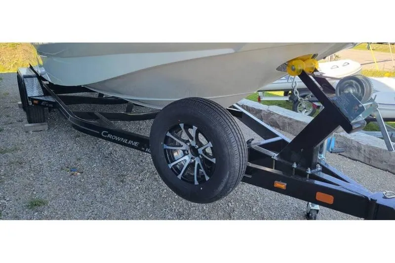 Slide: The Image of 2024 Crownline Eclipse E235 boat on trailer, showcasing hull and wheel details. - 26