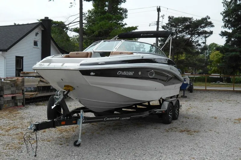 Slide: The Image of 2024 Crownline Eclipse E235 boat on trailer, parked outdoors near a house. - 6
