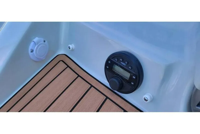 Slide: The Image of 2024 Crownline Eclipse E235 boat dashboard with audio controls and teak-style flooring. - 8