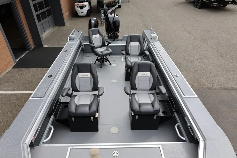 Slide: The Image of 2025 Thunder Jet 209 Rush OT boat interior with four gray seats, parked outdoors. - 36
