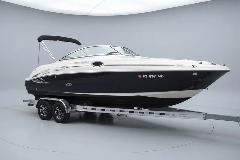 The Image of 2006 Sea Ray 240 Sundeck boat on trailer, sleek design, black and white exterior. - 0