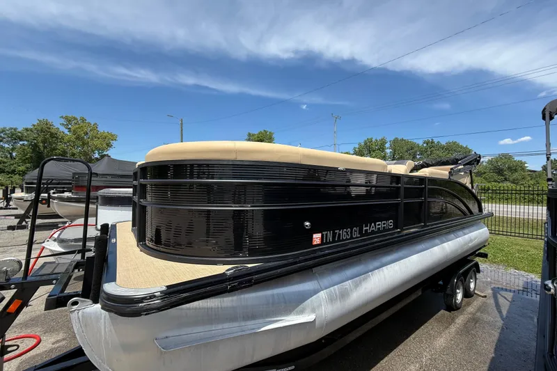 The Image of 2023 Harris Cruiser 230 pontoon boat on trailer under clear blue sky. - 0