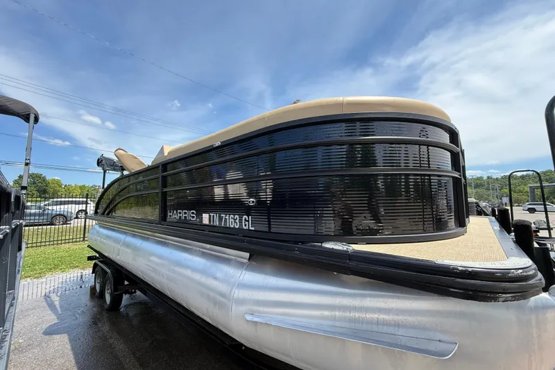Slide: The Image of 2023 Harris Cruiser 230 pontoon boat on trailer under a clear blue sky. - 2
