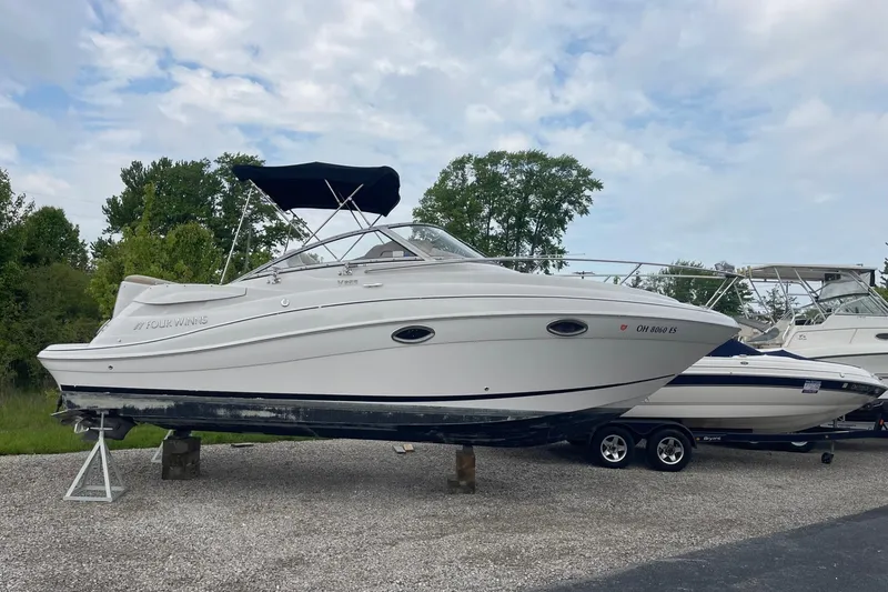 The Image of 2009 Four Winns V258 boat on trailer, parked outdoors with trees in background. - 0
