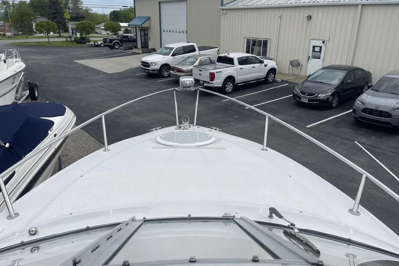 Slide: The Image of Bow view of 2009 Four Winns V258 boat at a marina with parked vehicles. - 27
