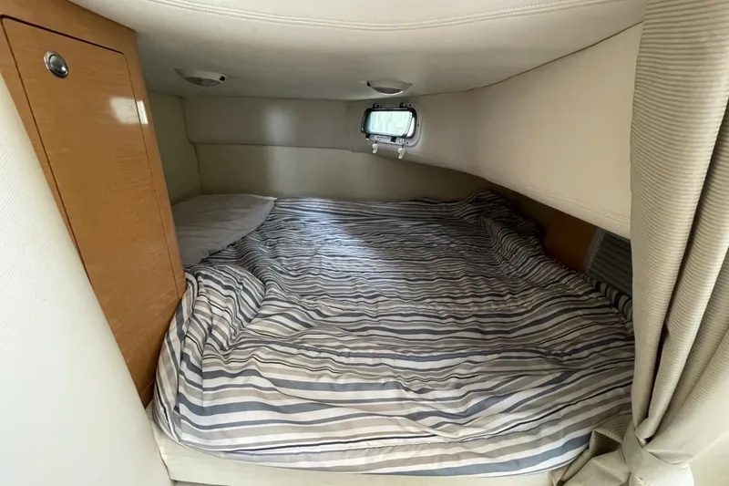 Slide: The Image of Cozy cabin bed in 2009 Four Winns V258 boat with striped bedding and small window. - 39