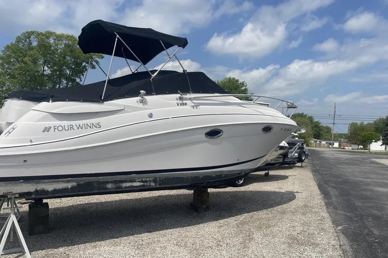 Slide: The Image of 2009 Four Winns V258 boat on display, featuring a sleek white design and black canopy. - 4