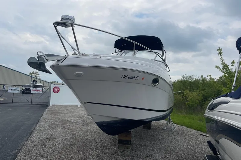 Slide: The Image of 2009 Four Winns V258 boat on display, parked on gravel under cloudy skies. - 5