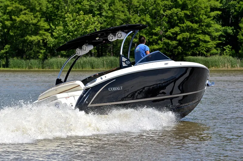 Slide: The Image of 2018 Cobalt R7 boat cruising on a lake with lush green trees in the background. - 5